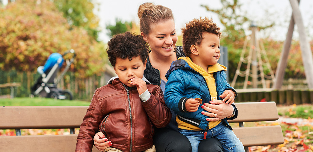 Alleenstaande moeder met 2 kinderen op een bankje in een speeltuin | Actueelbericht: ‘Waar is die village waar iedereen het over heeft?’