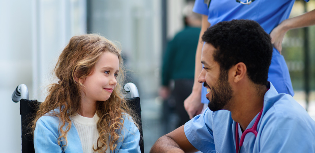 Kind in rolstoel kijkt tevreden naar verpleger van de SEH - Actueelbericht: Betere signalering van kindermishandeling op spoedeisende hulpen in Europa