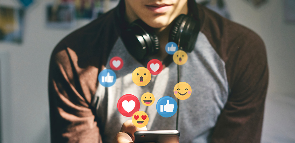 Jongen ontvangt verschillende emoji's op zijn mobiel na post. | Actueelbericht - Over emoji’s, straattaal en écht luisteren naar jongeren