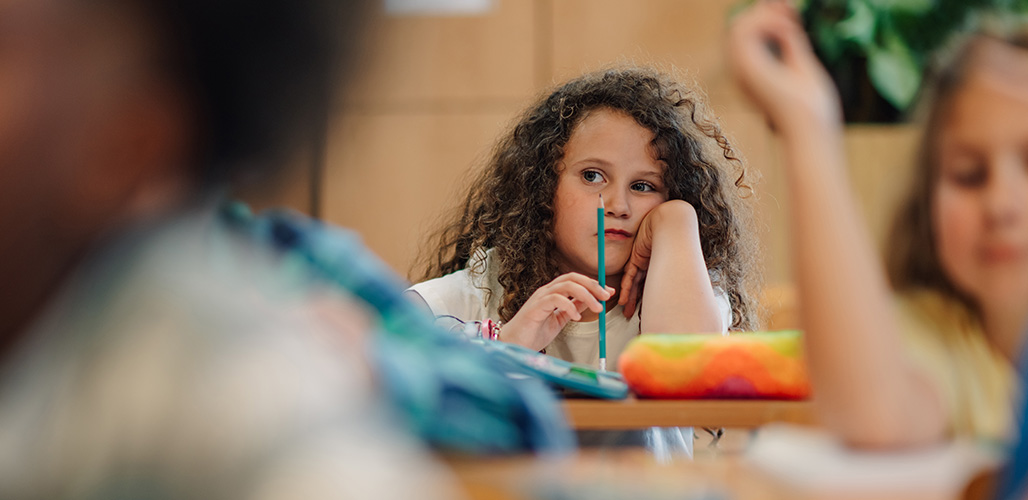 Meisje zit in de klas na te denken terwijl andere de les volgen | Actueelbericht: Waarom is Handle with Care zo waardevol?