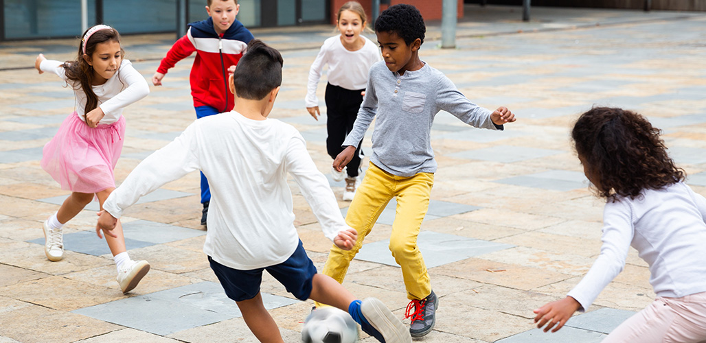 Kinderen voetballen buiten op het schoolplein | De invloed van sport en cultuur op de mentale gezondheid van jongeren