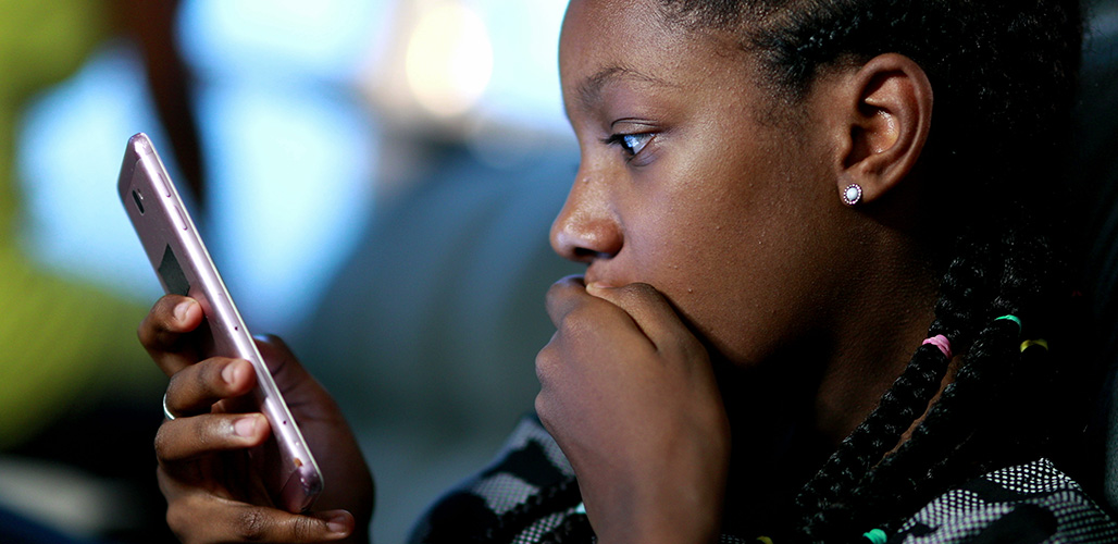Meisje kijkt geschokt naar een bericht wat zij via haar mobiel ontvangen heeft.