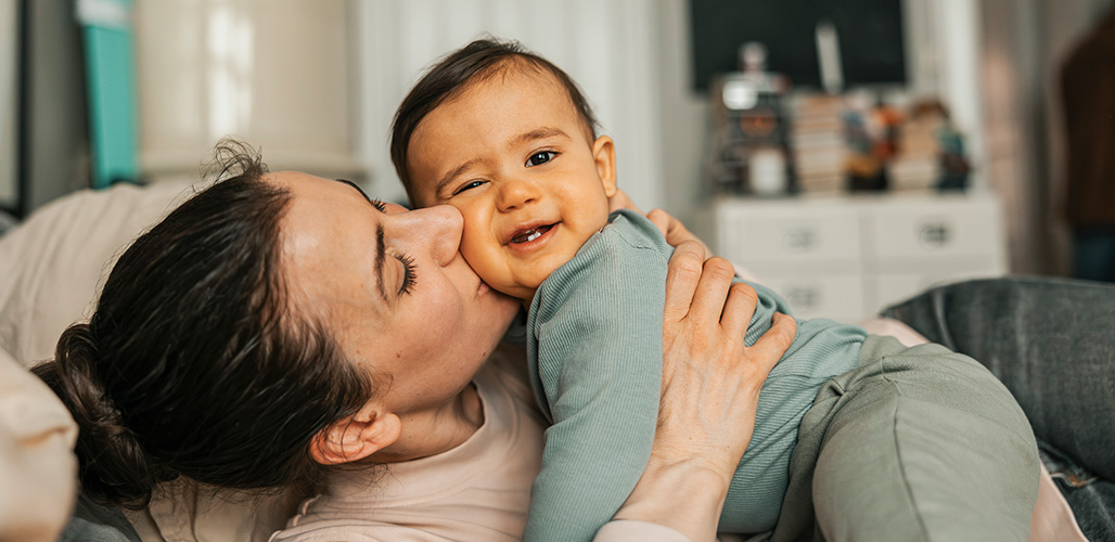 Moeder knuffelt baby liggend op de bank | Kansrijke start - Nieuwe cursus: 1e 1000 dagen