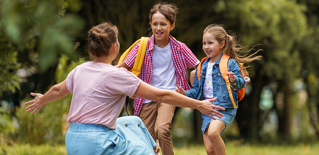 Moeder zit klaar om kinderen te omhelzen die komen aanrennen. | Verlies kinderen met ingrijpende ervaringen niet uit het oog