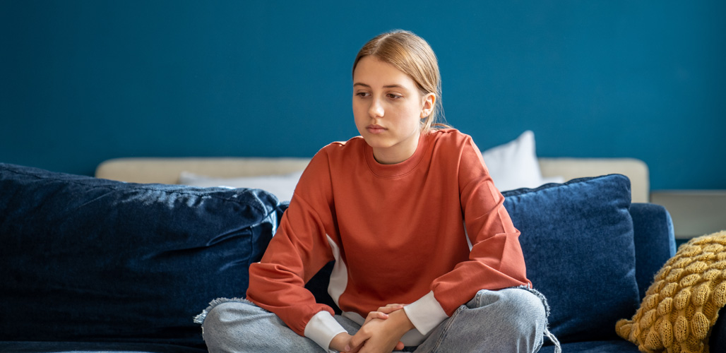 Meisje zit bedenkelijk op de bank | Actueelbericht: Tachtig procent van de kinderen die geweld meemaken, krijgt geen hulp