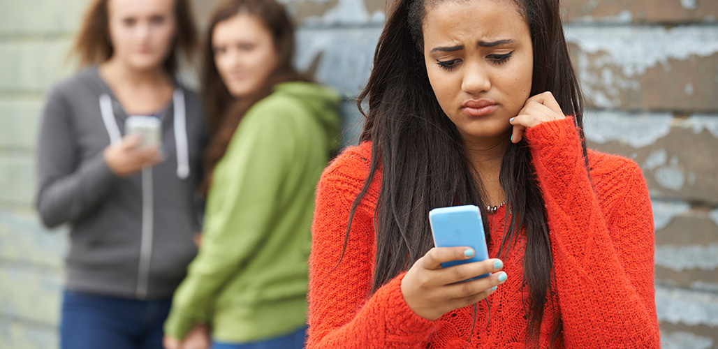 Meisje kijkt bezorgd naar een online bericht op haar mobiele telefoon | Hoe ga je online criminaliteit door jongeren tegen?