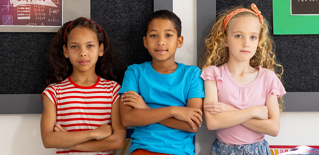 3 serieuze kinderen staan met armen over elkaar in de klas | Actueelbericht: Praten met kinderen over oorlog