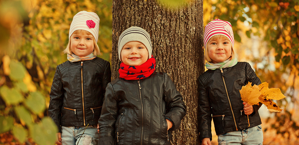 3 jonge kinderen leunend tegen een boom in de herfst. | Actueelbericht: Terugblik op de Week tegen Kindermishandeling 2025 