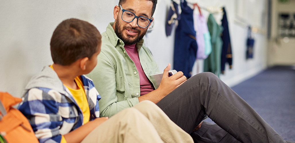 Leraar praat zittend op de gang met een leerling over zijn schoolsituatie | Actueelbericht: Chronisch letsel door pesten.