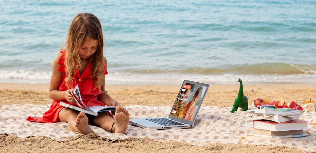 Meisje op het strand leest een boek op kleedje | Actueelbericht: Zomerse lees-, luister-, en kijktips plús Augeo cadeautips 