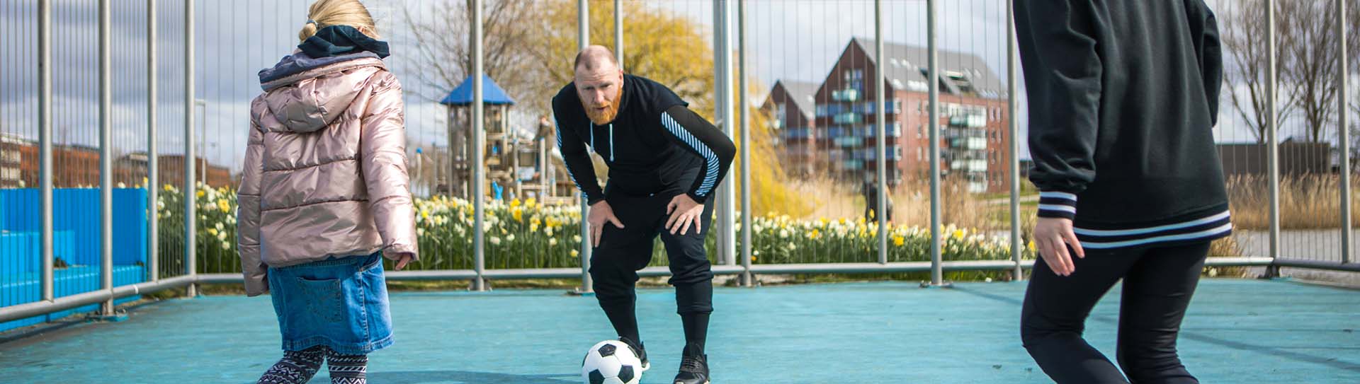 Wijkteammedewerker voetbalt met 2 meisjes