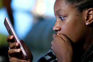 Meisje kijkt geschrokken naar haar mobiele telefoon