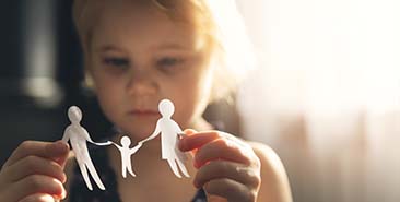 Wat is kindermishandeling - kind speelt met papieren poppetjes en maakt gelukkige familie