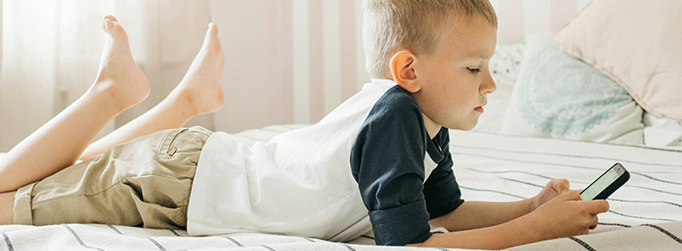 jongen ligt op bed een app te bekijken