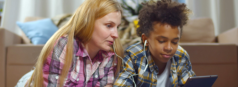 Mentaal welzijn en jongeren | Moeder en zoon luisteren samen naar muziek via oortjes op zijn mobiel