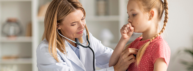 Vrouwelijk arts luistert naar het kuchen van een jonge patiënte via stethoscoop